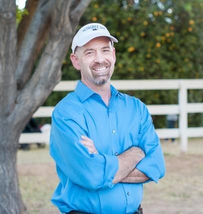 handsome man with folded arms in an orchard